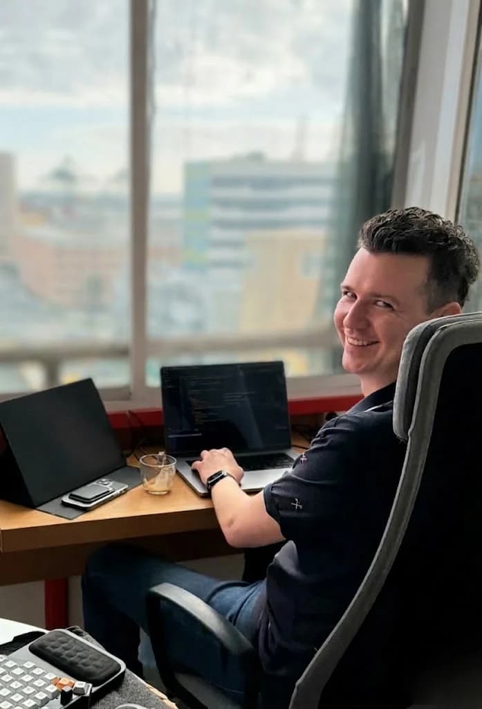 Darius aan het werk achter zijn laptop, met uitzicht over de stad